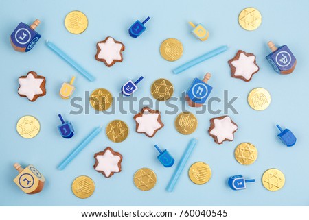 Blue background with multicolor dreidels, menora candles and chocolate coins. Hanukkah and judaic holiday concept. Horizontal