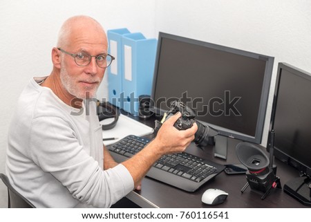 a photographer with camera at office with computer