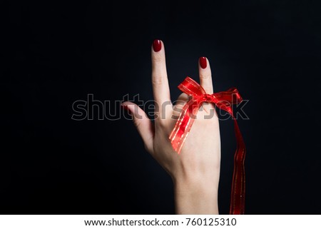 Woman hand giving the devil horns gesture on black background