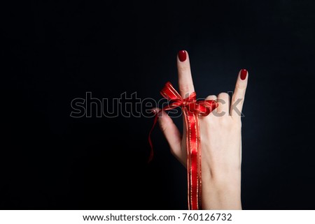 Woman hand giving the devil horns gesture on black background