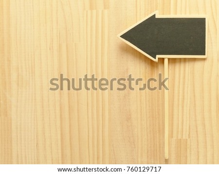 arrow shape of chalkboard putting on the wooden table 