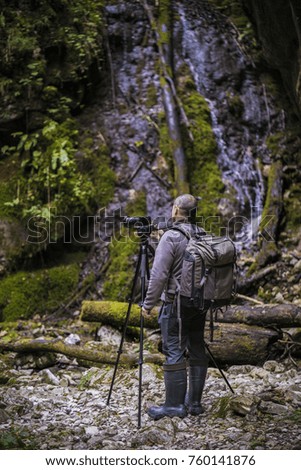 Professional photographer with cameras on tripod shooting in a river
