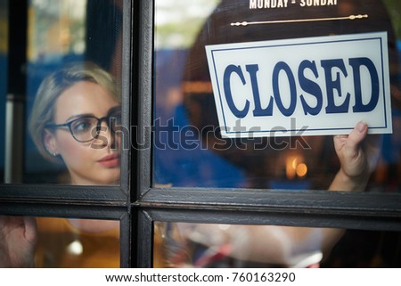 Pretty young shop owner turning closed sign