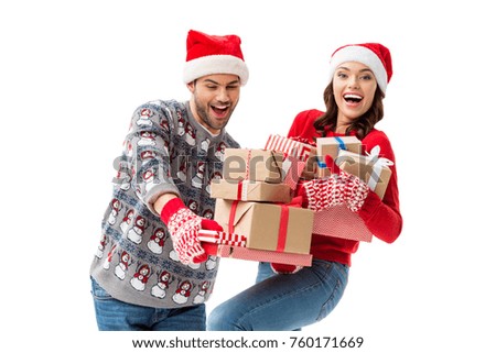 smiling young couple holding stacks of christmas gifts isolated on white
