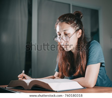 Tired students woman reading a book and writing book are stressed on table desk . Learning Overwork and stressful life concept .
