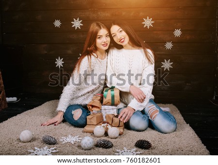 Two pretty girls posing for the camera with gifts for Christmas