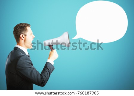 Side view of handsome young businessman screaming into megaphone on blue background with empty speech/thought cloud. Mock up. Communication and information concept