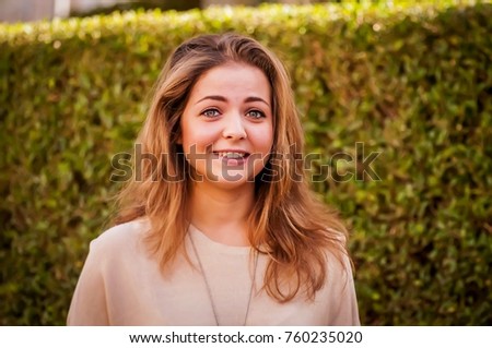 Shy pretty Caucasian girl outside with a light smile. Long and curly hair stock image.
