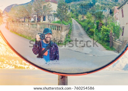 Reflection in a round mirror of a bearded photographer on the street