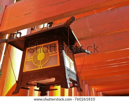 Japanese traditional vintage lantern with red wooden piles tunnel