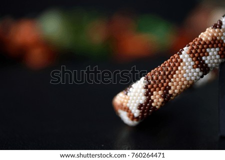 Camouflage bracelet made of seed beads on a dark background close up