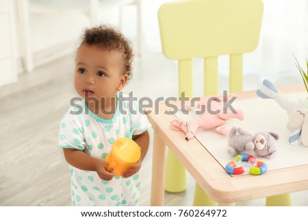 Cute baby with bottle of water indoors