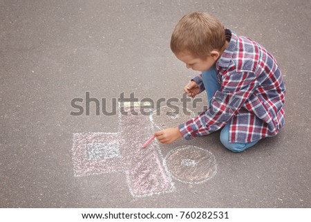 Little boy drawing car with chalk on asphalt