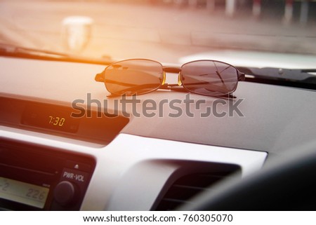 The concept of using sunglasses during travel : Sunglasses used in cars : Close up sunglasses placed on the car panel.