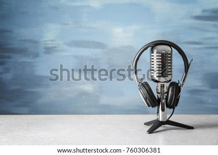 Retro microphone and headphones on table against blue wall