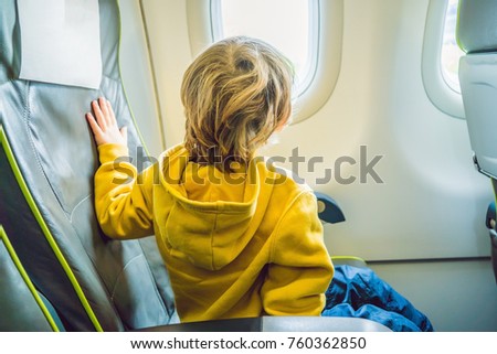 little boy in the plane looking out the window.
