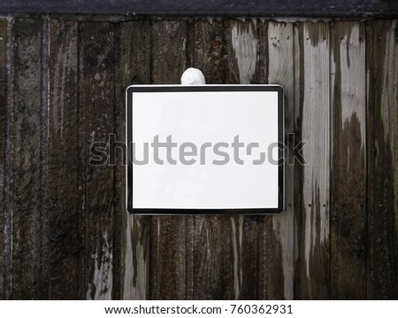 Blank white square sign on a frozen wall made of wooden planks.