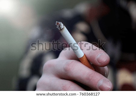Smoking a cigarette. Smoking is harmful to health. Image of cigarette in man hand