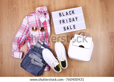 Female hipster clothing and white backpack on the floor with lightbox black friday sale text flat lay