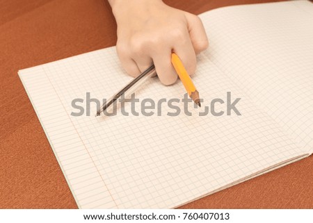The hand of a schoolgirl holding pencil and pen.