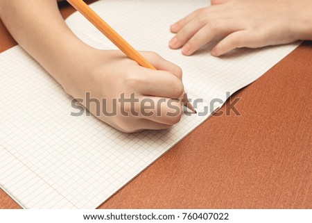 The hand of a schoolgirl writes a pen in notebook.