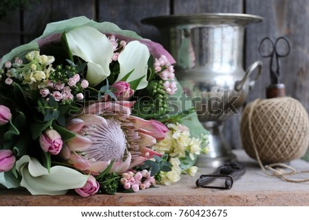 Floral scene with fresh bouquet of pink, green, white flowers, vintage secateurs, string twine holder with scissors on aged wooden background, daylight, original photo