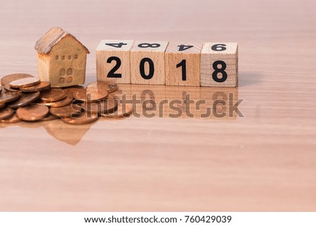 The wooden cube for new year with the house model and coins on wooden background
