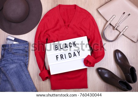 Set of stylish winter female clothes on wooden floor background with light box flack friday text top view