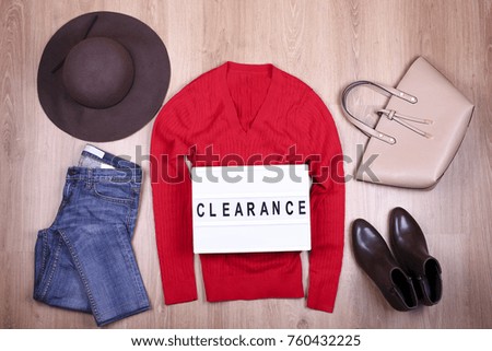 Set of trendy winter female clothes on wooden floor background with lightbox clearance text 