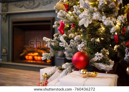 Close-up photo with decorations of christmas tree against a house fireplace. Selective focus (Narrow depth of field). Christmas red balls on a christmas tree branch. New Year's concept