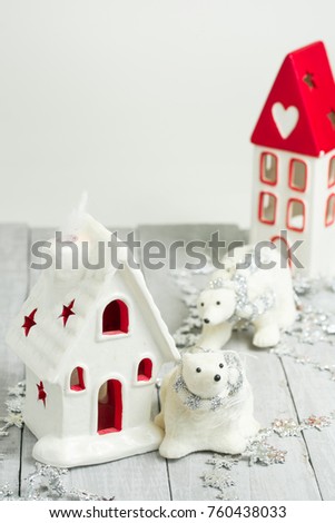 New year decoration. Tiny Christmas houses.
Christmas background with white ceramic house, snowflakes, star, garlands and decorations on wood background.