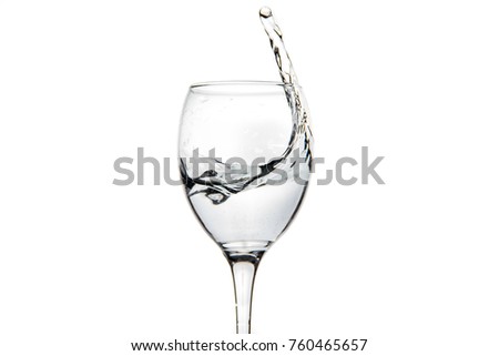 Wineglass with splashing drops of fresh water - motion freeze close-up picture isolated on the white background.