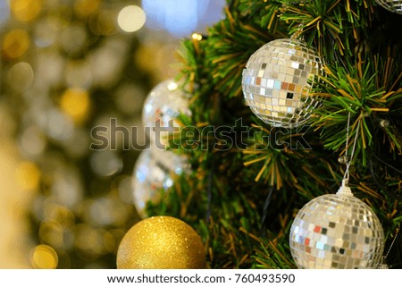 Many mirror balls decorate on green leaves tree and lighting system in a department store in greeting season such as Christmas and New Year festival 