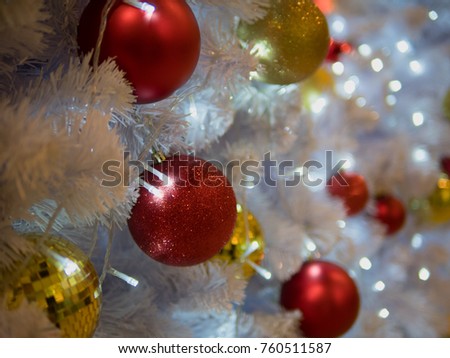 Closeup of red bauble hanging from a decorated Christmas tree.