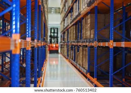 Warehouse and a modern system of targeted storage of products and goods. Electric forklift between large shelving in a modern storage building. Selective focus.