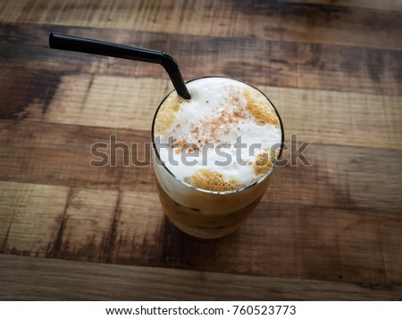 Iced coffee with milk foam on wooden table