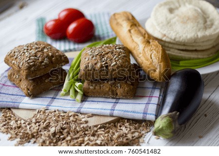 fresh bread with sunflower seeds, baguettes and tomatoes on a wooden table