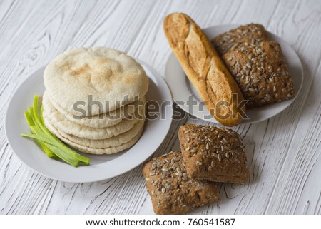 white and black bread and baguette on a wooden table