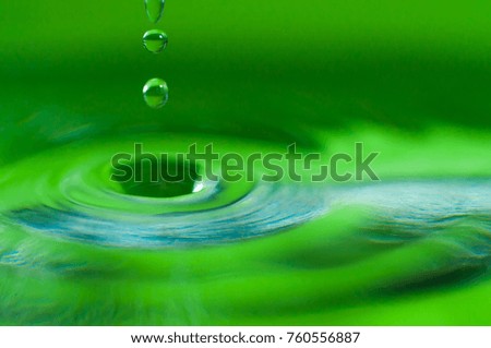 Water drop in focus, macro close up shot isolated on green background.