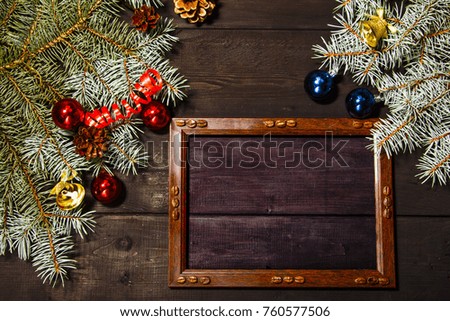 Christmas background with a spruce branch on an old black board and a frame for text. View from above