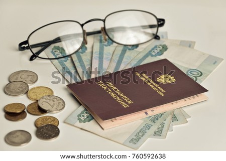money, glasses and pension certificate on a wooden surface / russian translation: russian pension fund. pensioner's certificate