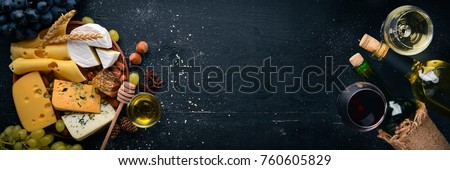 Assortment of cheeses, a bottle of wine, honey, nuts and spices, on a wooden table. Top view. Free space for text. Royalty-Free Stock Photo #760605829