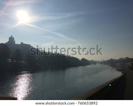 This is a photo of the big and long river on the nice day in winter. It is surrounded by trees and building. It is so beautiful and nice photo. 