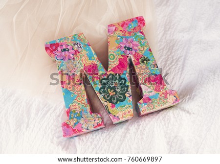 A very beautiful wooden 3d letter M on a white textured backdrop. A letter from the alphabet, the letter M