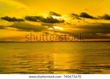 A beautiful yellow sunset over Tampa Bay, Florida vacation destination.  Sunbeams penetrate the clouds for a beautiful colorful horizon with a stunning reflection on the water