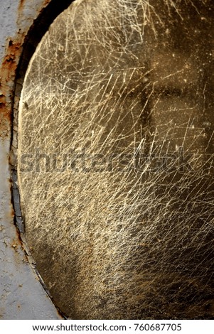 Close up portrait picture of a small dark cross reflected in scratched glass surface, captured in a cemetery in USA