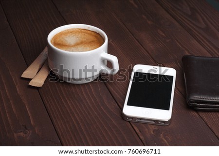 Smartphone with notebook and cup of strong coffee on wooden background. Cell phone with writing set with espresso