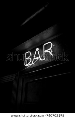 Neon inscription BAR on the wall. Neon inscription BAR in different colors. Multicolored neon inscription BAR on dark background. Black and white photo
