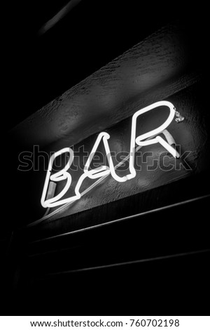 Neon inscription BAR on the wall. Neon inscription BAR in different colors. Multicolored neon inscription BAR on dark background. Black and white photo