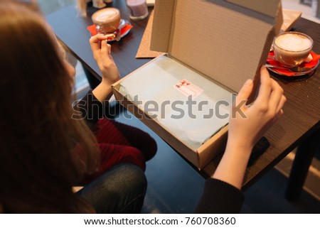 the girl prepares Christmas gifts for his family: a notebook. decorate a surprise in a cozy coffee shop. on the table scattered cones, garland with lights. healthy and clean hands closeup